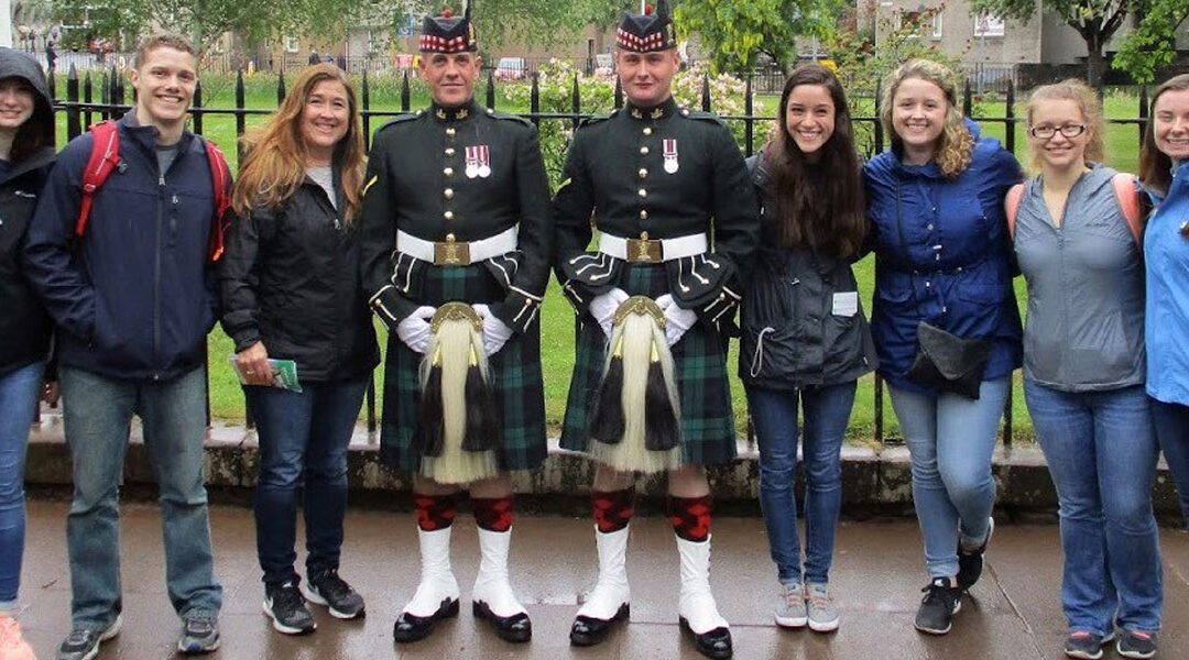 Kent State College of Nursing students and faculty member in Edinburgh, Scotland with two guards outside of the palace.