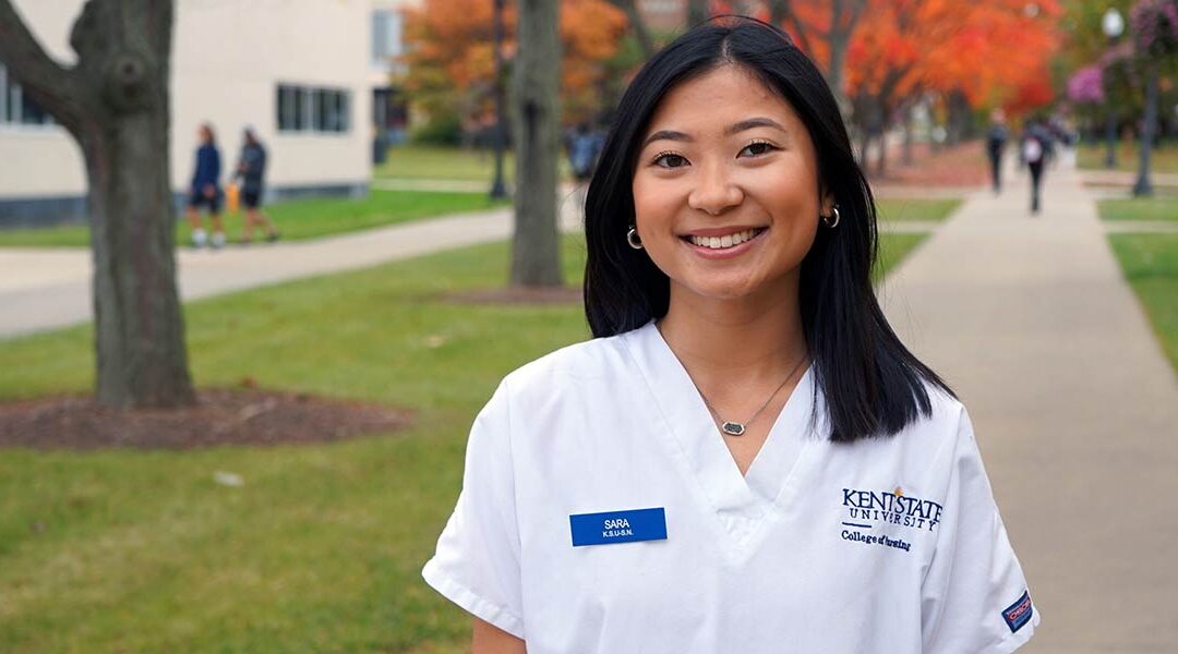 Sara Peterson stands outside in her Kent State nursing scrubs.
