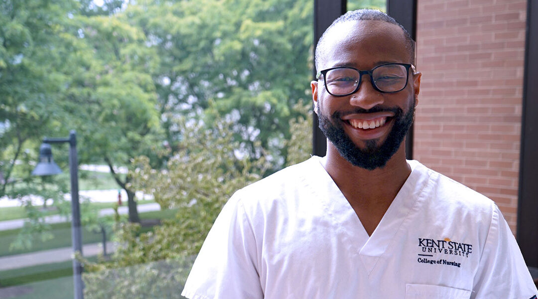 Marcellus Byrd, BSN ‘23, wears his Kent State University College of Nursing scrubs, smiling for a photo in Henderson Hall on the Kent Campus.