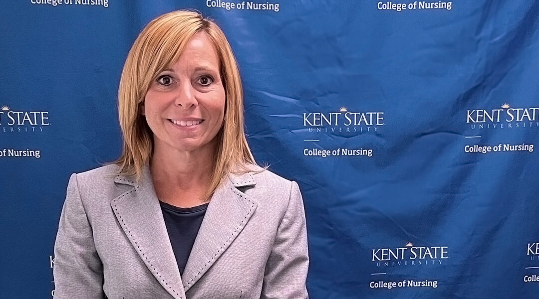 Cindy Wilk, standing in front of a Kent State University College of Nursing branded backdrop, prepares to present her Ph.D. research during the fall 2024 semester.