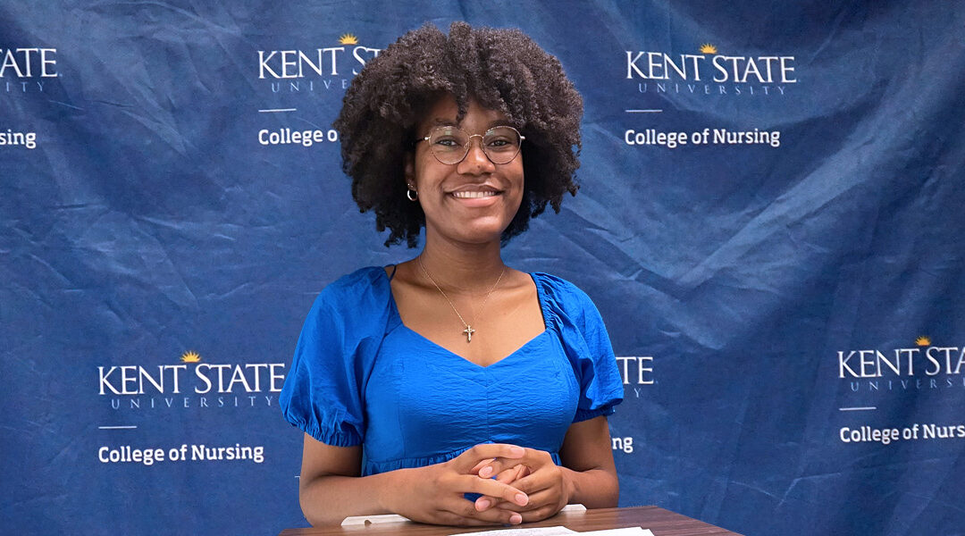 Trinity Rudolph stands in front of the Kent State University College of Nursing branded backdrop before giving her presentation.